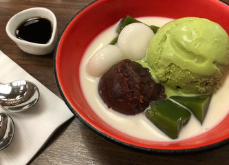Top view of green tea matcha icecream scoop with red beans mochi and milk in red bowl, Japanese traditional dessert