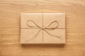 Small gift box wrapped in kraft paper on wooden table