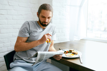 Man Reading Newspaper While Having Breakfast At Home