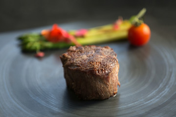 Grilled beef steak with asparagus. Juicy thick grilled beef steak. Vegetables on a black plate