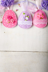 Handmade patchwork pink and lilac felt easter eggs on white wooden table