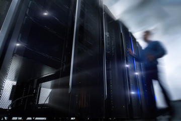 Shot of in Large Data Center Full of moving and working people. Pronounced Motion Blur. Computer Engineer Opening Server Rack Door In Data Center. 