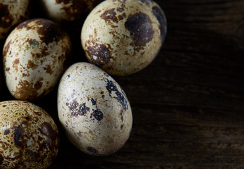 Obraz premium Spotted quail eggs arranged on the background of old wooden boards, with copy-space, selective focus.