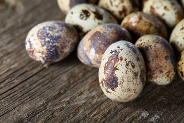 Spotted quail eggs arranged on the background of old wooden boards, with copy-space, selective focus.