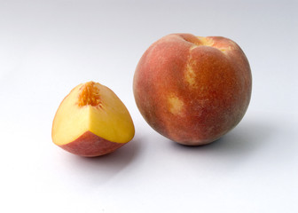 Whole peach and slice of peach against white