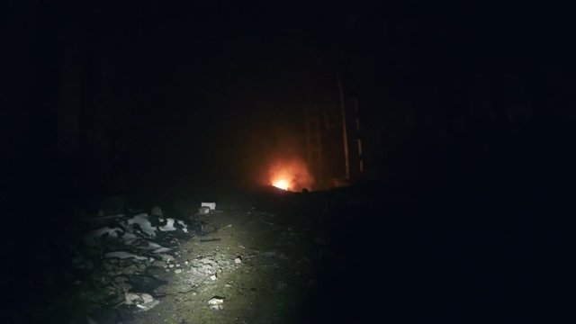 Moving forward, first person view, going with flashlight in large dark abandoned industrial warehouse holl to real fire, shake effect