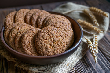 Oat cookies in a plate on dark wooden background. Healthy food, breakfast, snack. Raw meal.