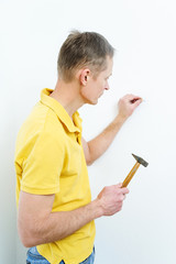 The man is putting a nail into the wall.