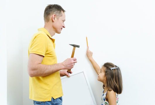 Father and daughter are hanging the picture.