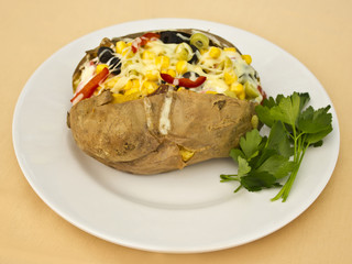 Baked kumpir potato stuffed with cheese, sausage, olives, peppers and corn