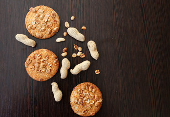 Cookies with peanuts and raw peanuts in shell on dark wooden background. Copy place, copy space