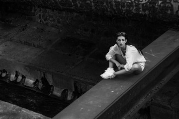 attractive woman in white clothes posing while sitting at abandoned building