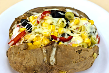 Baked kumpir potato stuffed with cheese, sausage, olives, peppers and corn
