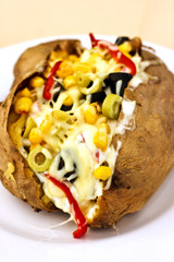 Baked kumpir potato stuffed with cheese, sausage, olives, peppers and corn