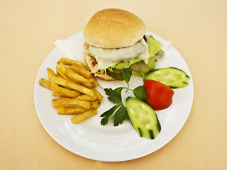 Cheeseburger with French fries, sliced cucumbers and tomatoes
