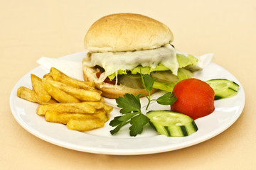 Cheeseburger with French fries, sliced cucumbers and tomatoes