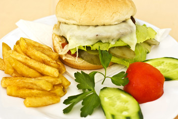 Cheeseburger with French fries, sliced cucumbers and tomatoes