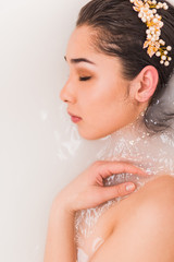 Naklejka premium Closeup portrait of a young woman relaxing in the milk water