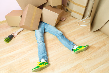 Picture of man in jeans lying under cardboard boxes