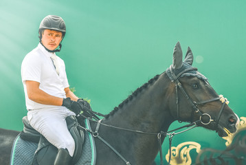 Showjumping competition, bay horse and rider in white uniform waits for performing jump over the...