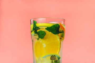 homemade cold lemonade with citrus and mint in glass on pink background