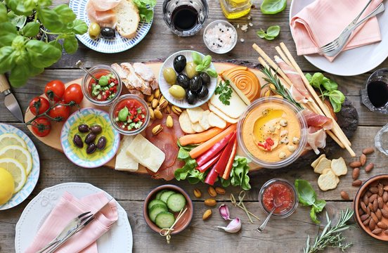 Mediterranean appetizers table concept. Diner table with tapas selection: cured meat and salami, gazpacho soup, jamon, olives, cheese, hummus and vegetables.   Overhead view.