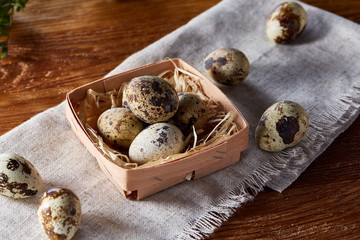 Quail eggs in a box on a rustic wooden background, top view, selective focus.