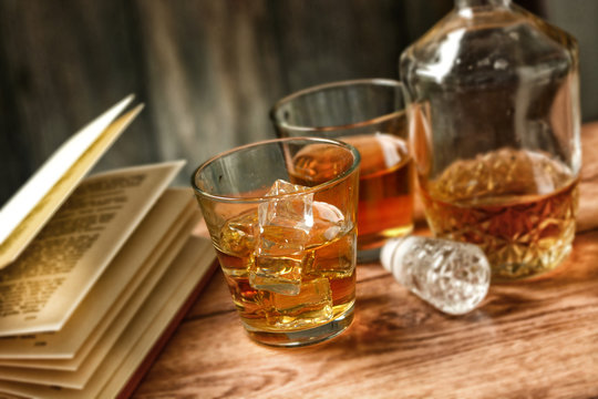 glasses of whiskey with ice and open book - selective focus