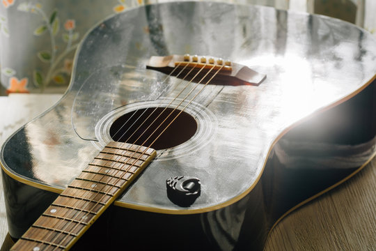 black acoustic guitar reflecting sun light