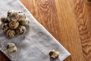 Quail eggs arranged in pyramid on a napkin over a wooden table, close-up, selective focus.