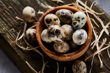 Obraz na płótnie Canvas Wooden bowl filled with quail eggs on wooden board over white background, close-up, selective focus.