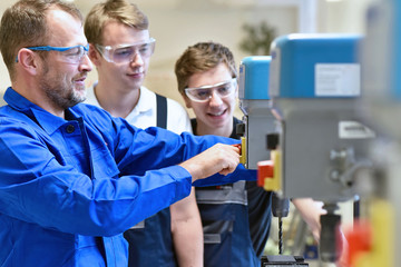 Group of young people in mechanical vocational training with teacher at drilling machine //...