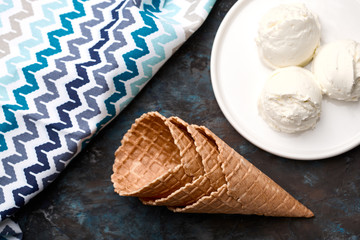 Ice cream balls, scoops and waffle cones on dark background. Advertising space.