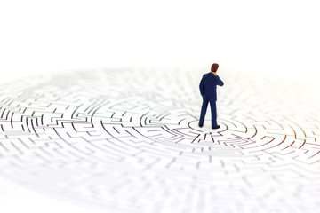 Miniature people: Businessman standing on center of maze. Concepts of finding a solution, problem...