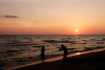Fototapeta premium Silhouette Couple love are shooting photo at the beach on sunset