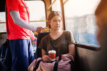 Young beautiful woman with glasses on top of her head looking through window and enjoying her...