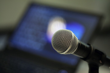 Closeup of microphone in a meeting room; selective focus background.