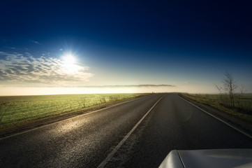 Summer Landscape with Field and Country Road Leading in the Fog. Dramatic Sky at Sunset Background. Beautiful Nature Background.