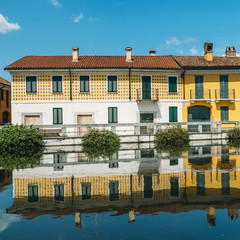 Fototapeta na wymiar Cityscape of Gaggiano, just outside of Milan. Colourful houses reflected in the Naviglio Grande canal waterway