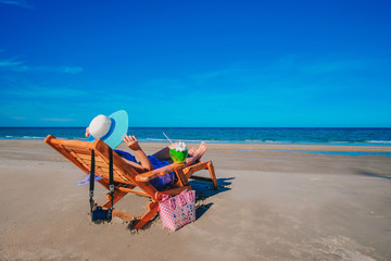 woman traveler in sexy swimming suit sitting on the chair and enjoying for view of the blue sea.sexy Asia lady drinking coconut juice on the beach on holiday.  