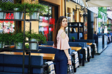 Naklejka na ściany i meble Portrait of a young girl in the city . Girl in jeans and blouse on the streets