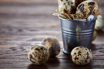 Small decorative bucket filled with quail eggs dark wooden table, close-up, selective focus.