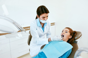 Stomatology. Dentist Working With Girl Teeth In Dental Clinic.