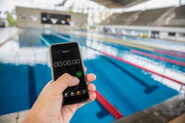 Coach hand with stopwatch training swimmer athlete at professional pool