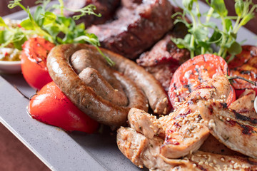 Assorted delicious grilled meat and sausages with vegetables .