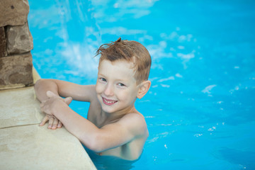 Fototapeta na wymiar Happy boy with red hair smiling sitting in pool