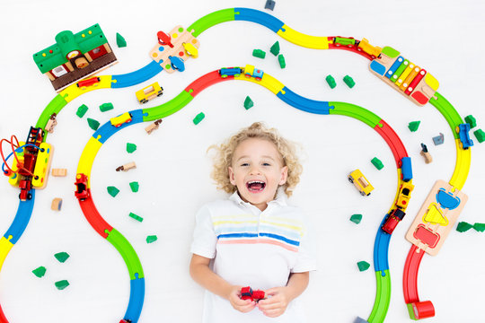 Child with toy train. Kids wooden railway.