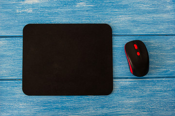 computer mouse pad and mouse on a blue wooden background © HENADZY