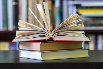 An open book on the background of bookshelves.