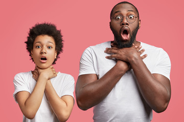 Shocked male teenager with Afro hairstyle and dark skinned man being fed up with everything, keep hands on necks as show suicide gesture, isolated on pink background. I am sick and tired of it!